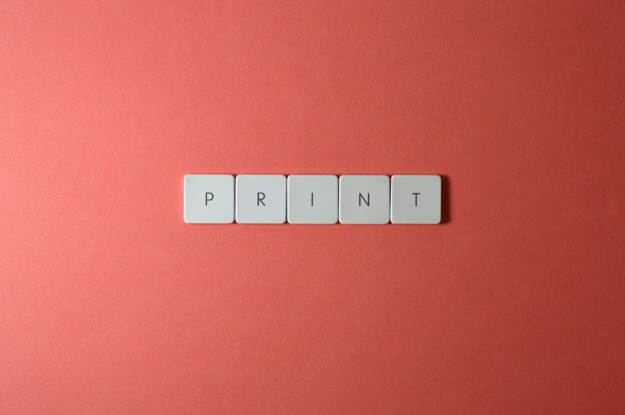 Minimalist arrangement of keyboard keys spelling 'PRINT' on a coral background.